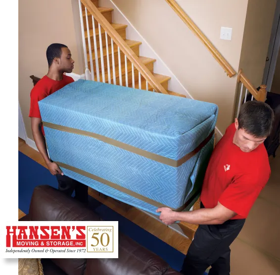 Two people carrying a mattress up a staircase